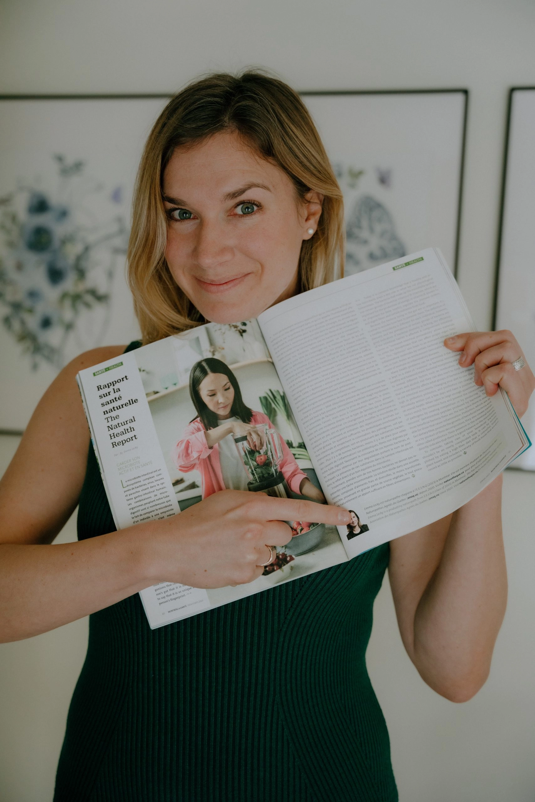 Femme souriante qui tient fièrement un magazine ouvert où elle pointe sa photo