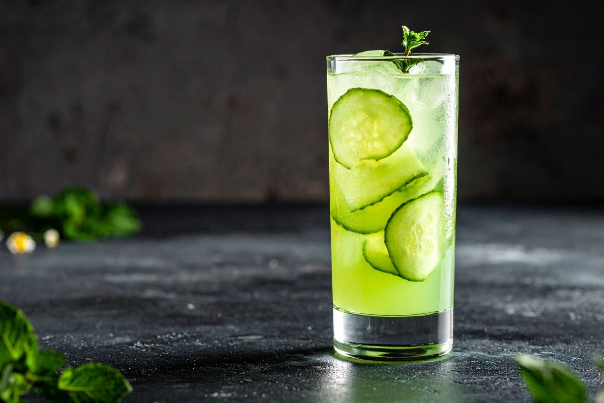 Verre en vitre avec eau, glaçons, feuilles de menthe fraiches et tranches de concombres