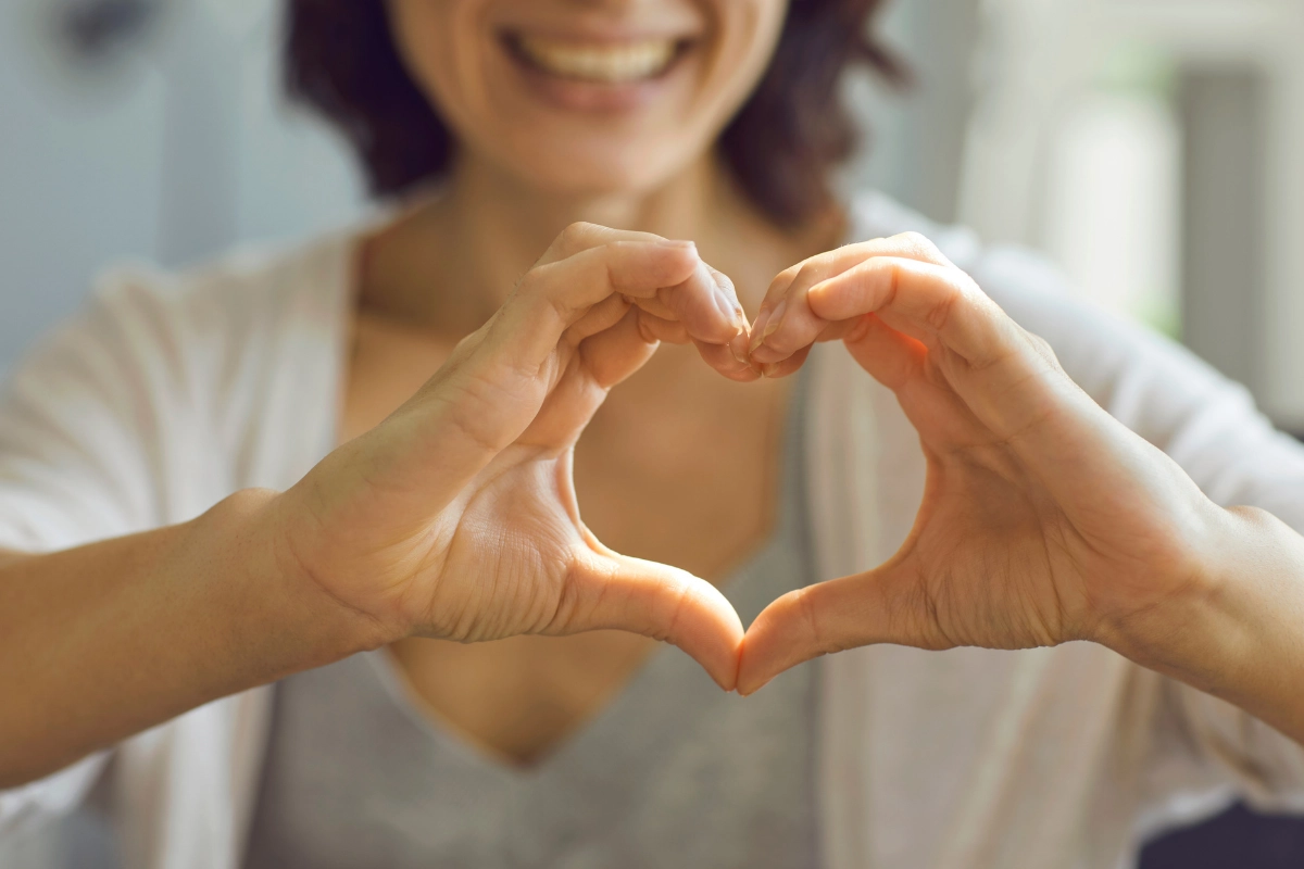 Femme qui fait un symbole de coeur avec ses mains
