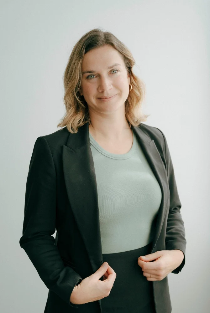 Femme souriante, veston noir et chandail vert sauge, cheveux blonds