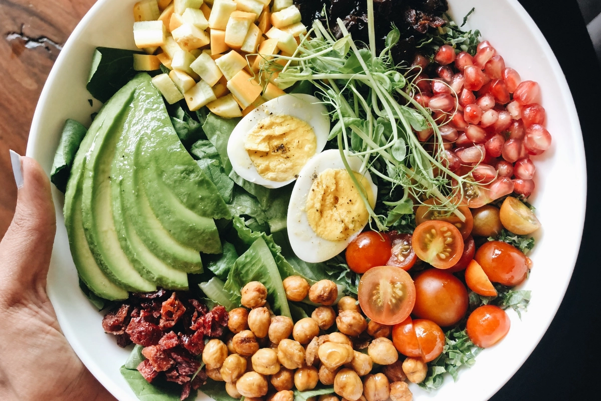 Bol santé avec oeufs, avocat, tomates cerises, grenades, pois chiches, courgette et pousses verts