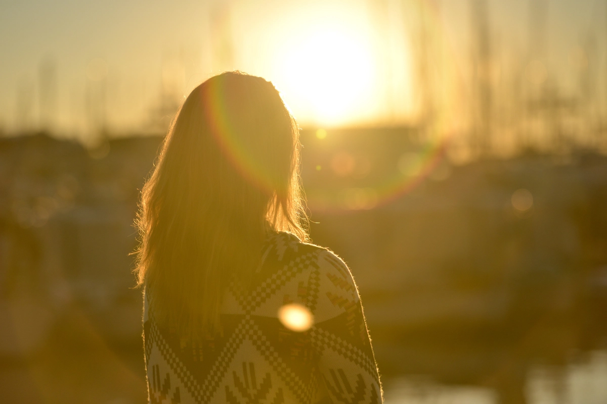 Silouhette de femme, de dos, devant un levé de soleil jaune