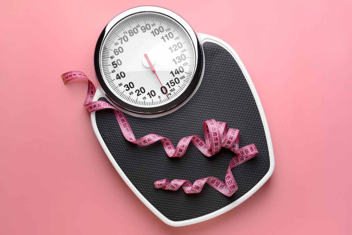 balance rose avec poids à 0 kg et ruban à mesurer